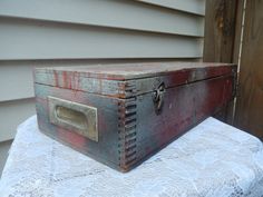 an old wooden box sitting on top of a white table cloth covered tablecloth in front of a house