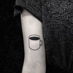 a black and white coffee cup tattoo on the left inner arm, which is outlined in a circle