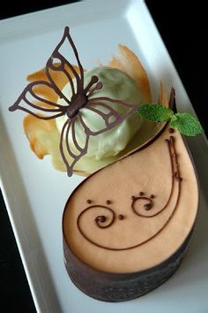 a white plate topped with a pastry covered in icing and a butterfly on top