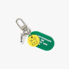 a green and yellow dog tag keychain on a white background with a silver metal hook