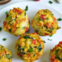 several small muffins on a white plate topped with cheese and veggies