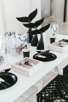 a white table topped with black vases and plates