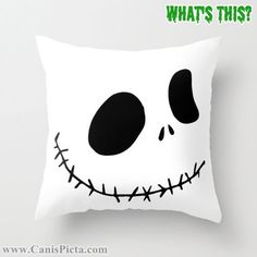 a white pillow with a black face and green lettering that says, what's this?