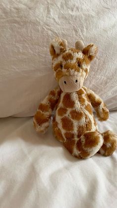 a stuffed giraffe sitting on top of a bed