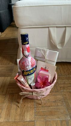 a bottle of liquor sitting in a basket on the floor next to a box and some other items