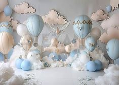 several blue and white hot air balloons are in the sky with clouds around them on display