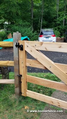 a wooden gate is open to reveal a car parked in the back yard behind it