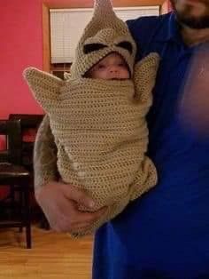 a man holding a baby wrapped in a crochet costume