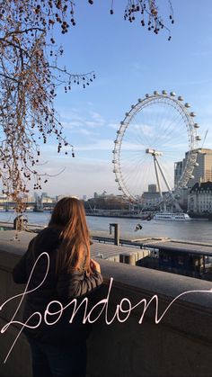 a woman looking out over the river thames in london, england with the london eye in the background