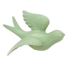 a green bird figurine sitting on top of a white surface