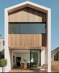 a modern house with wooden floors and large windows on the front of it, surrounded by grass