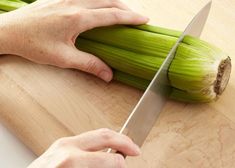 a person is cutting up some celery on a wooden board with a knife