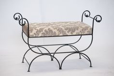 a wrought iron bench with a patterned seat cover on it's backrest and foot rest