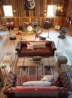 a living room filled with lots of furniture next to a drum set on top of a hard wood floor