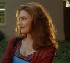 a woman standing in front of a house wearing a blue and red dress with flowers on it