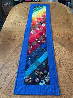 a table runner made out of different colored fabrics on top of a wooden dining room table