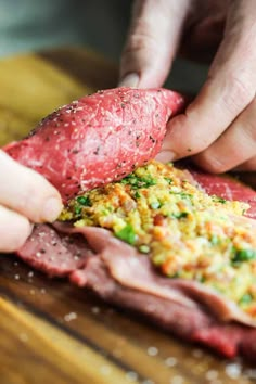 a person cutting up meat on top of a wooden table