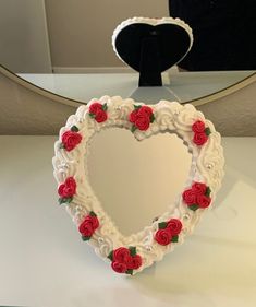 a heart shaped mirror sitting on top of a table