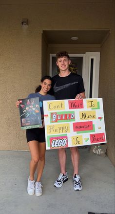 two people holding up a large sign in front of a door with words written on it