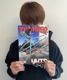 a person holding up a magazine with a skateboarder on it's face