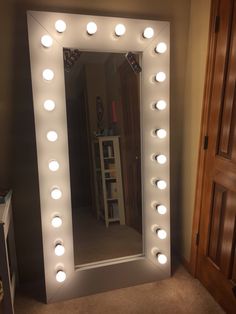 a large lighted mirror in a room with lights on it's sides and doors