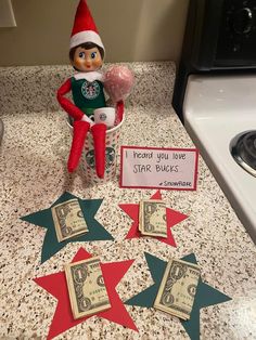 an elf is sitting on the counter next to some money