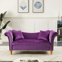 a purple couch sitting in front of two pictures on the wall