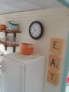 a clock mounted to the side of a wall next to a white refrigerator freezer