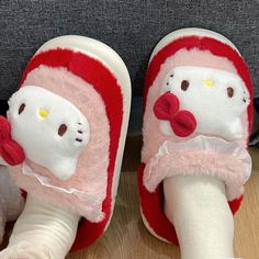 a pair of hello kitty slippers with bows on the bottom and feet, sitting on a wooden floor