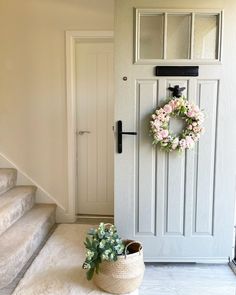 a white door with a wreath on it next to some stairs and a planter