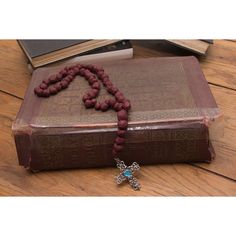 a book with a cross on it sitting on a wooden floor next to a rosary