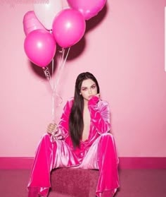 a woman in pink is sitting on a bench with balloons