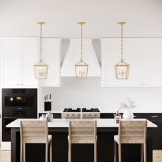 a kitchen with black and white cabinets, gold pendant lights over the island countertop