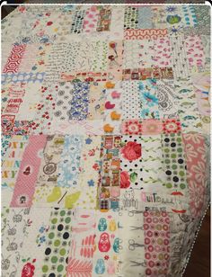 a quilted table cloth covered in lots of different colored patches and dots on it