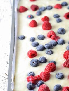 a cake with berries and blueberries on it in a pan, ready to be baked