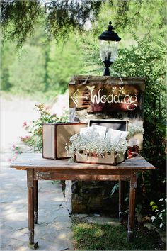 an old fashioned tv sitting on top of a wooden table next to flowers and trees