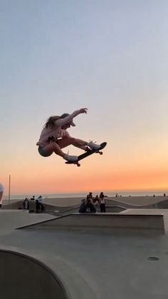 a skateboarder is doing a trick in the air over a ramp at sunset