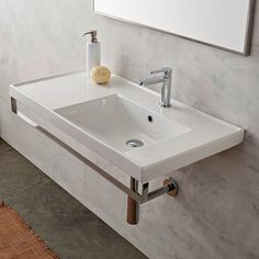 a white bathroom sink sitting under a mirror next to a wall mounted faucet