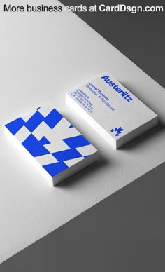 two business cards on top of each other with blue and white squares in the middle