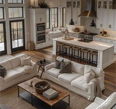 a living room filled with furniture next to a kitchen and dining room table in front of an open floor plan