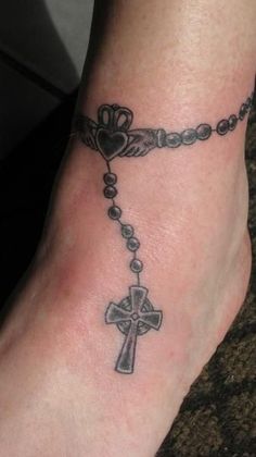 a foot with a cross and heart tattoo on it's side, along with a rosary