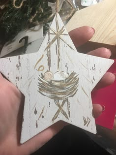 a hand holding a wooden star ornament with a nativity scene on it