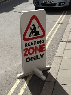 a sign that reads reading zone only on the side of the road next to a car