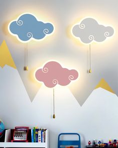 three clouds are hanging from the ceiling above a book shelf and toy chest in a child's room