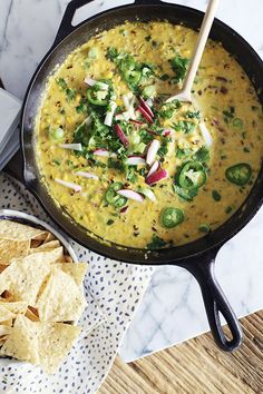 a skillet filled with tortilla chips and guacamole next to a bowl of salsa