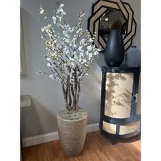 a vase filled with white flowers sitting on top of a wooden floor next to a mirror