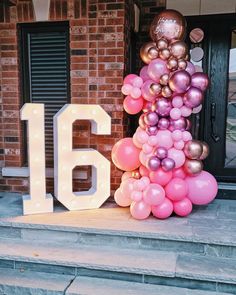 a large number is made out of balloons on the front steps of a house with a sign that says 16