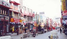 a city street filled with lots of signs and people walking down the sidewalk next to buildings