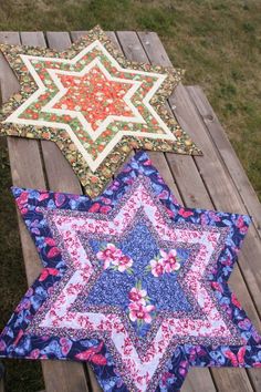 three star shaped quilts sitting on top of a wooden bench