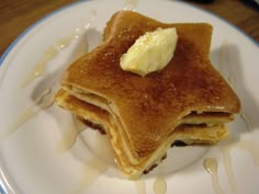 a stack of pancakes on a plate with butter and syrup drizzled around it